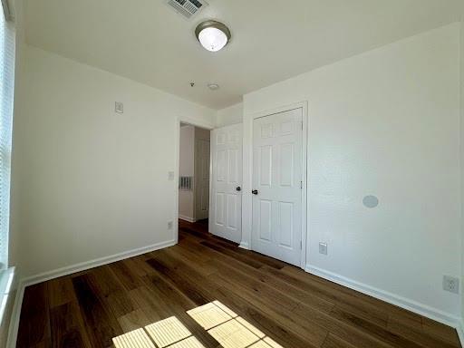 944 SE 14th St, Oklahoma City, OK 73129 - unfurnished bedroom with a closet, wood finished floors, visible vents, and baseboards