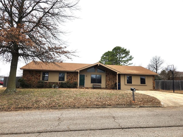 ranch-style home featuring concrete driveway and fence