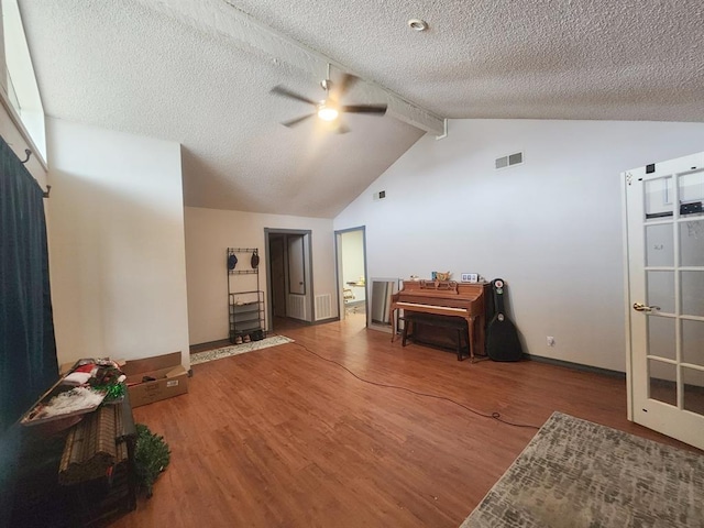 sitting room with visible vents, a ceiling fan, wood finished floors, vaulted ceiling with beams, and a textured ceiling