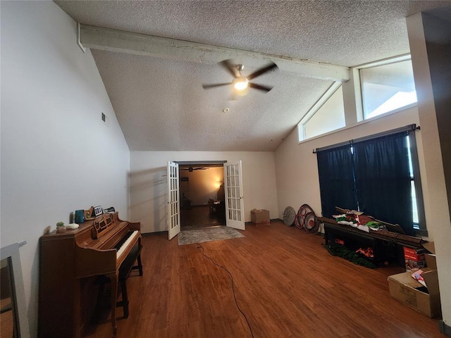 living area with vaulted ceiling with beams, a textured ceiling, wood finished floors, a ceiling fan, and french doors