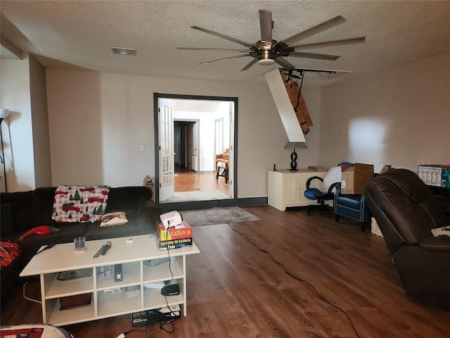 living room with ceiling fan, a textured ceiling, visible vents, and wood finished floors