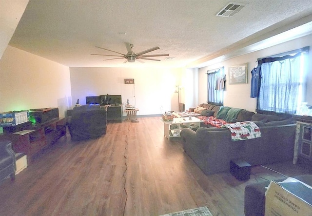 living area featuring visible vents, ceiling fan, a textured ceiling, and wood finished floors