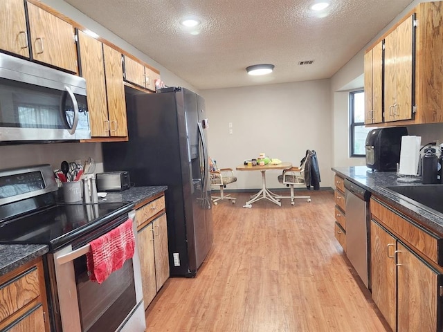 kitchen featuring dark countertops, light wood finished floors, and stainless steel appliances