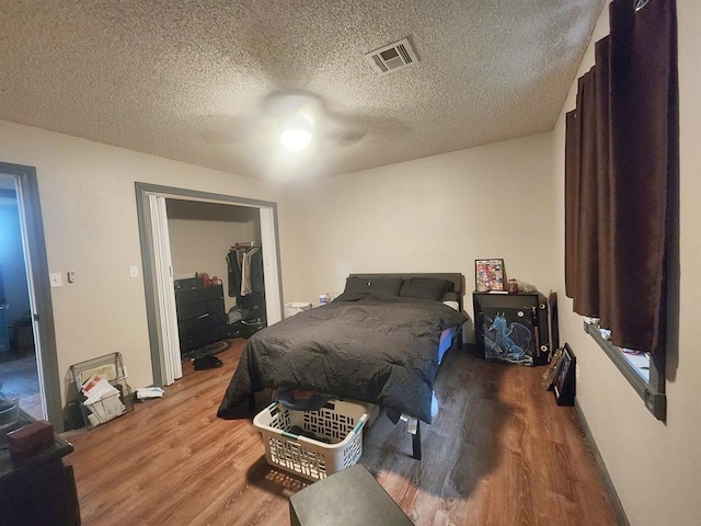 bedroom with visible vents, a textured ceiling, and wood finished floors