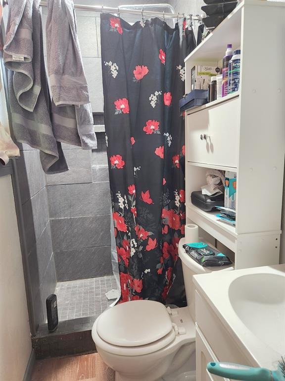 full bathroom featuring toilet, a shower stall, wood finished floors, and vanity