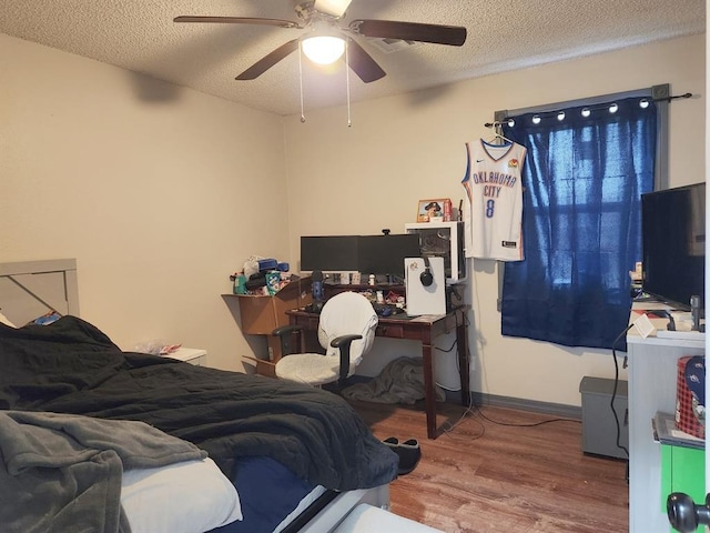 bedroom featuring ceiling fan, a textured ceiling, baseboards, and wood finished floors