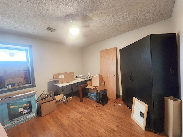 office space featuring a textured ceiling, visible vents, and wood finished floors