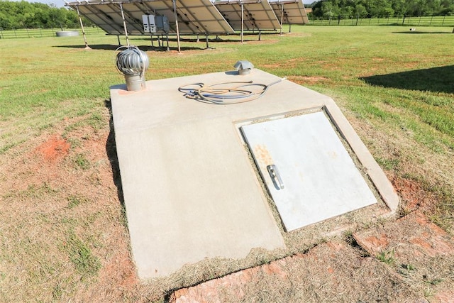 entry to storm shelter featuring a yard, a rural view, and fence