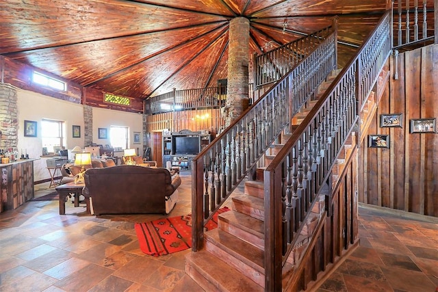 living room with high vaulted ceiling, stone tile flooring, wood ceiling, and stairs