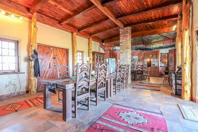 dining room with vaulted ceiling with beams, wooden ceiling, decorative columns, and stone finish flooring