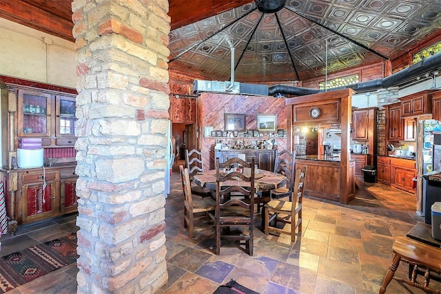 dining space with an ornate ceiling, stone finish flooring, and a towering ceiling