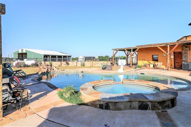 view of swimming pool with a pool with connected hot tub, a patio area, fence, and central air condition unit