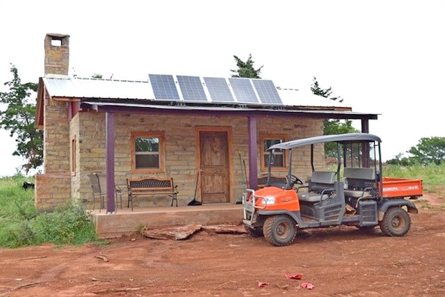 exterior space featuring roof mounted solar panels and a chimney