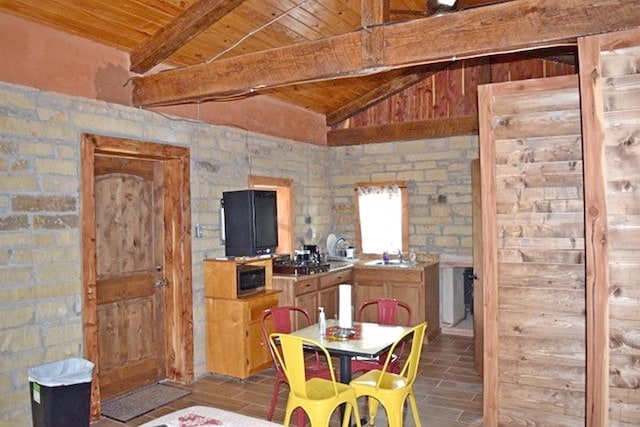 dining space featuring vaulted ceiling with beams, wooden ceiling, and wood finished floors