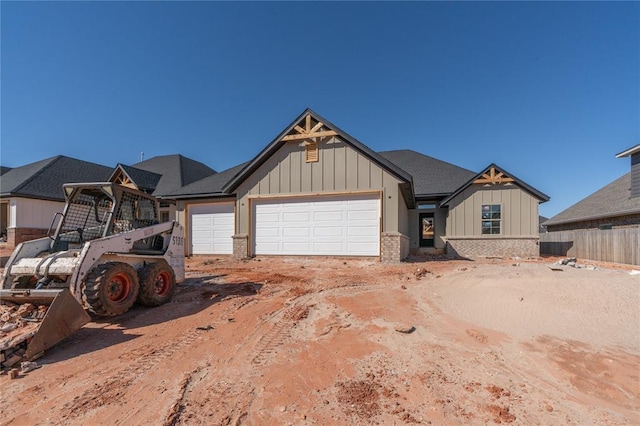 view of front facade with brick siding, an attached garage, board and batten siding, fence, and driveway