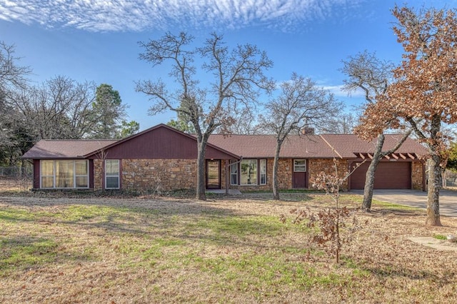 view of front of home with stone siding, driveway, a front lawn, and a garage