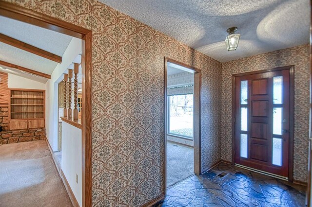 foyer featuring wallpapered walls, lofted ceiling with beams, carpet floors, and a textured ceiling