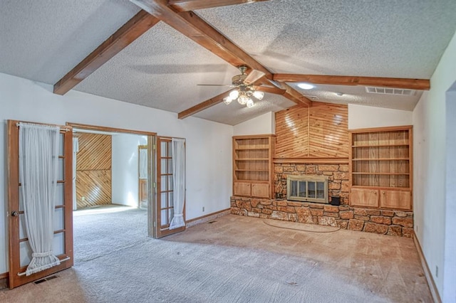 unfurnished living room featuring a stone fireplace, a textured ceiling, lofted ceiling with beams, and visible vents