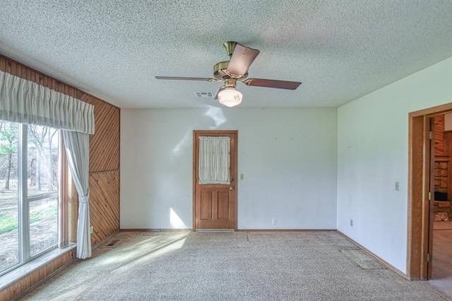 unfurnished room with visible vents, carpet floors, a textured ceiling, and wood walls