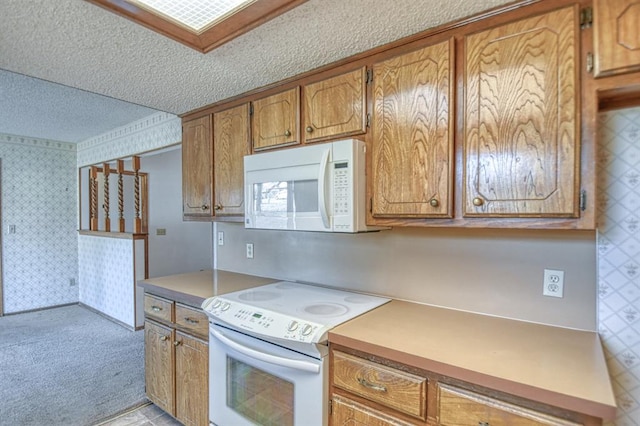 kitchen featuring white appliances, brown cabinetry, wallpapered walls, a textured ceiling, and light colored carpet