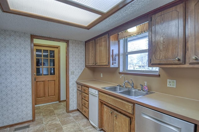 kitchen with wallpapered walls, a textured ceiling, and a sink