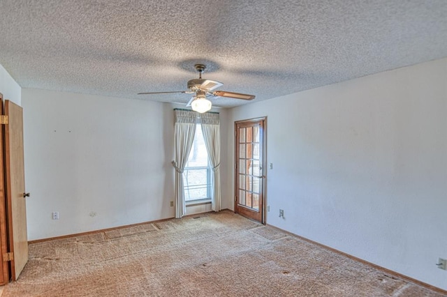 spare room featuring a textured ceiling, light colored carpet, baseboards, and ceiling fan