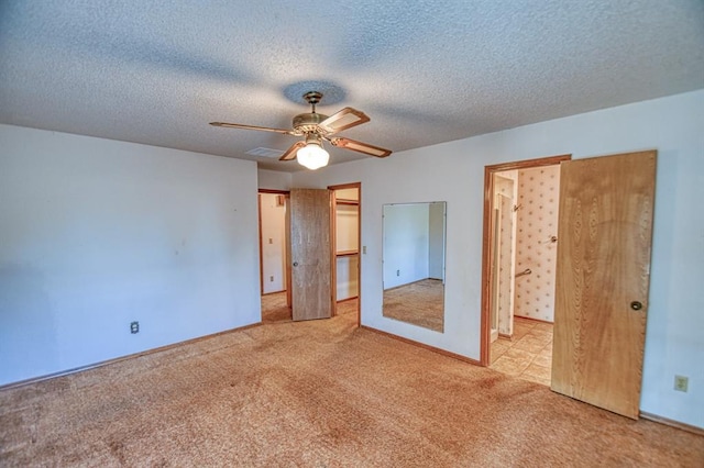 unfurnished bedroom featuring ceiling fan, visible vents, carpet floors, and a textured ceiling