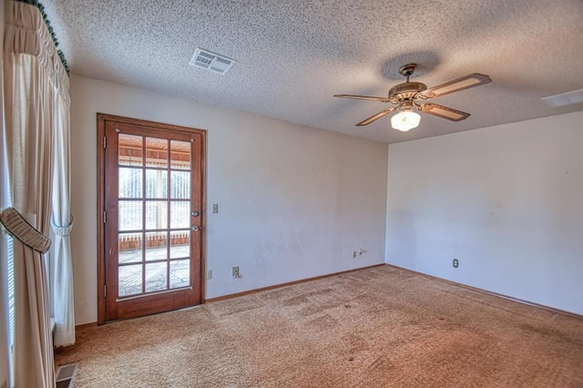 spare room featuring a ceiling fan, visible vents, carpet floors, and a textured ceiling