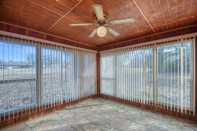 unfurnished sunroom with wooden ceiling, a ceiling fan, and a wealth of natural light