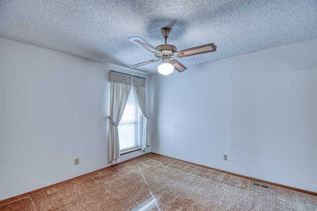 carpeted empty room with visible vents, baseboards, a textured ceiling, and ceiling fan