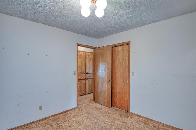 unfurnished bedroom with a textured ceiling, baseboards, a closet, and light carpet