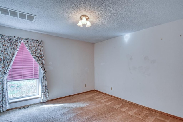 carpeted empty room with visible vents, a textured ceiling, and baseboards