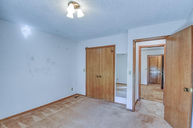 unfurnished bedroom with a closet, light colored carpet, and a textured ceiling