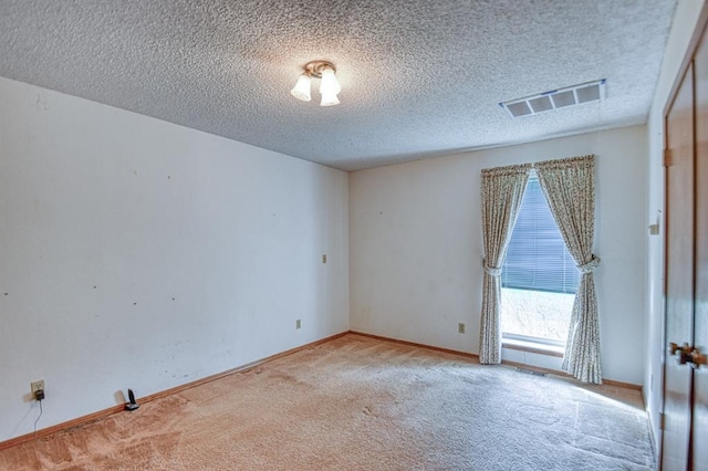 spare room featuring visible vents, a textured ceiling, baseboards, and carpet