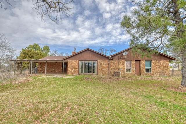 back of property with stone siding, a patio, a chimney, and a yard