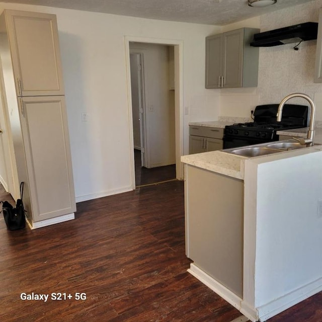 kitchen with gas stove, gray cabinets, light countertops, and dark wood finished floors