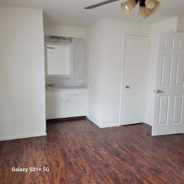 unfurnished bedroom featuring dark wood-type flooring, a sink, a textured ceiling, and baseboards