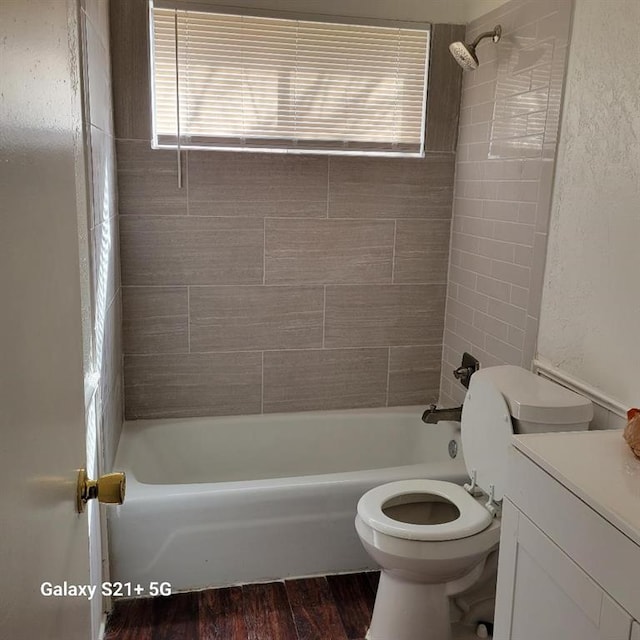 bathroom with shower / washtub combination, a textured wall, toilet, vanity, and wood finished floors