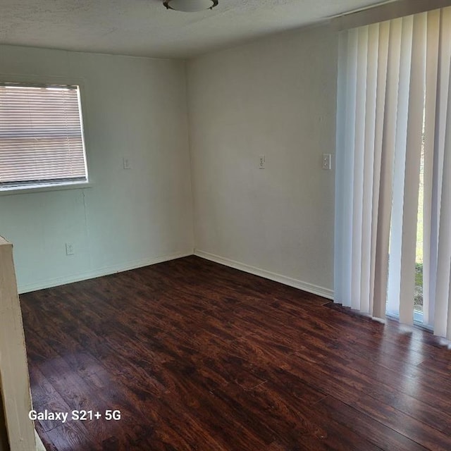 spare room with dark wood-type flooring and baseboards