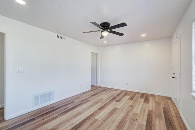 spare room with light wood-type flooring, baseboards, and visible vents