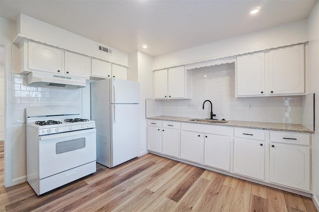 kitchen featuring white appliances, visible vents, light wood-style flooring, under cabinet range hood, and a sink