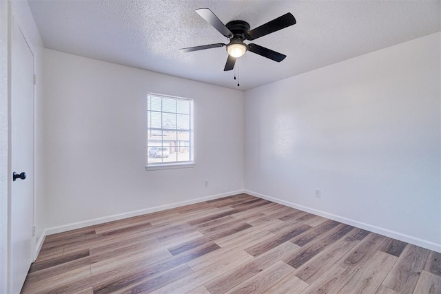 spare room with baseboards, ceiling fan, light wood-style flooring, and a textured ceiling