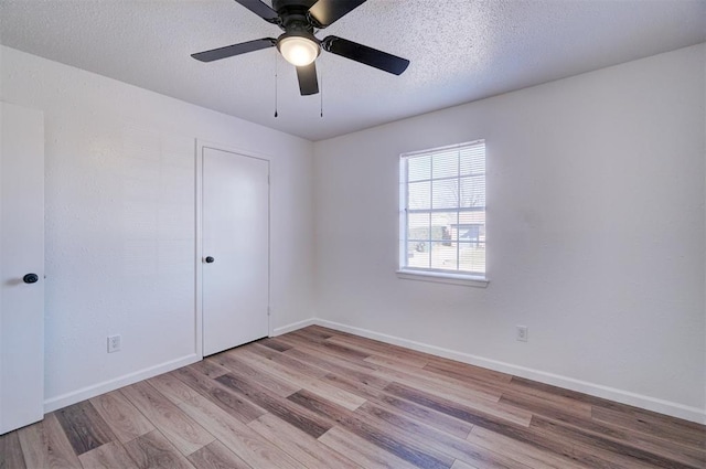 unfurnished room with a textured ceiling, baseboards, and wood finished floors