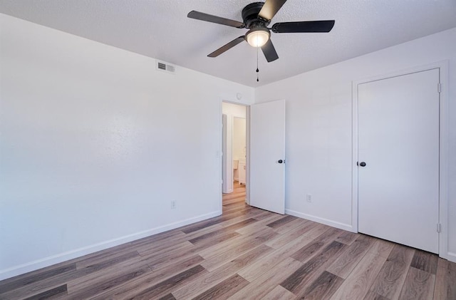 unfurnished bedroom with baseboards, visible vents, a ceiling fan, a textured ceiling, and light wood-style floors