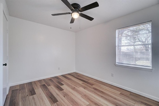 spare room featuring a wealth of natural light, baseboards, and wood finished floors