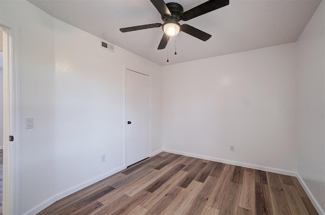 spare room featuring visible vents, ceiling fan, baseboards, and wood finished floors