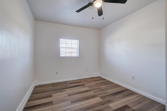 spare room featuring wood finished floors, a ceiling fan, and baseboards