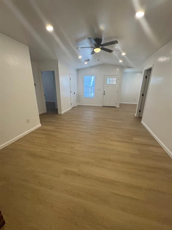 unfurnished living room with light wood-style flooring, baseboards, vaulted ceiling, and a ceiling fan