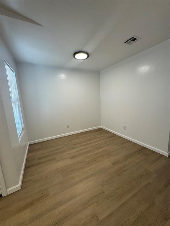 spare room with visible vents, baseboards, and wood finished floors