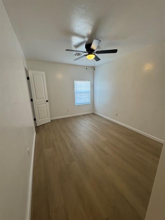 spare room featuring ceiling fan, wood finished floors, and baseboards